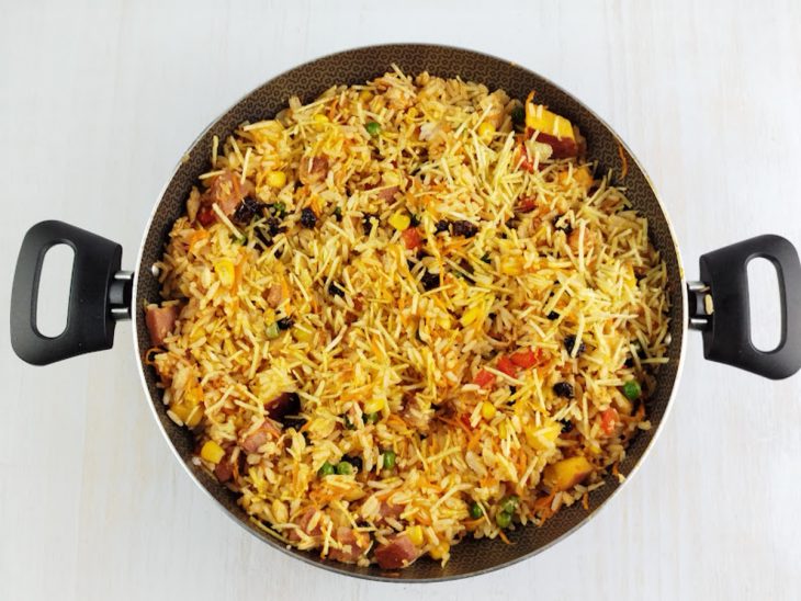 Na panela, salsinha e batata palha sendo adicionadas.