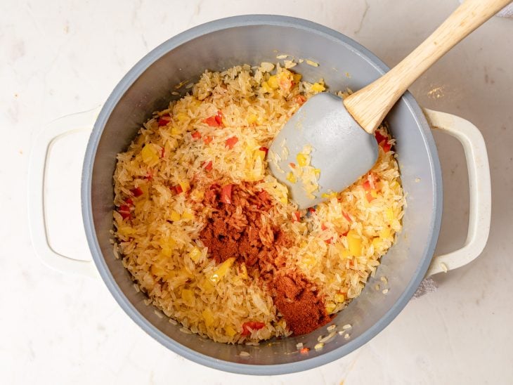 Uma panela com o refogado de legumes, arroz e temperos.