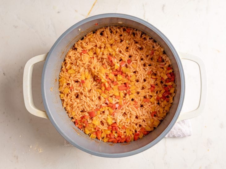 Uma panela com o refogado de legumes, arroz e temperos.
