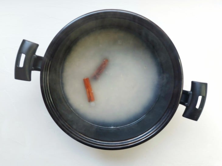 Uma panela com arroz, água fervendo e paus de canela.