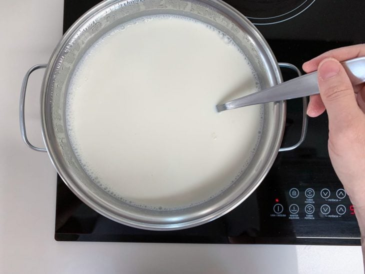 Panela com leite sendo mexido com uma colher.