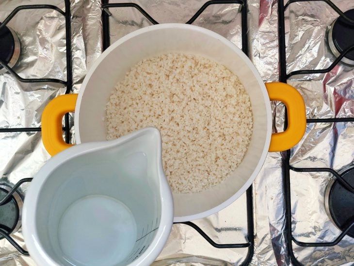 Panela com arroz e água sendo adicionada para cozinhar.