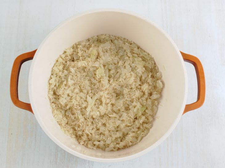 Numa panela, o arroz sendo refogado.