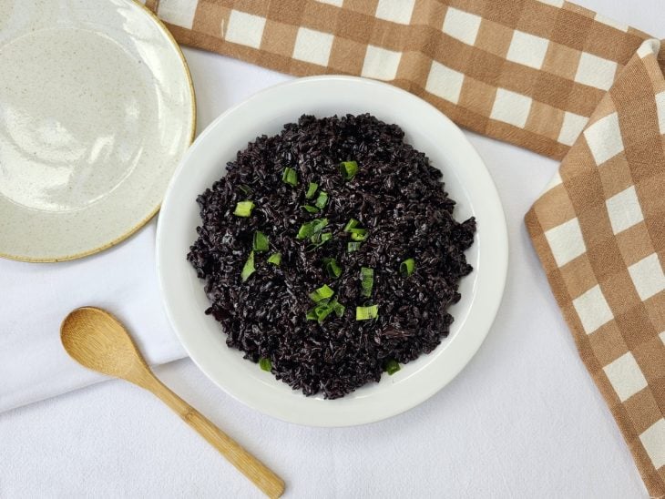 Arroz negro servido em um recipiente redondo e branco.