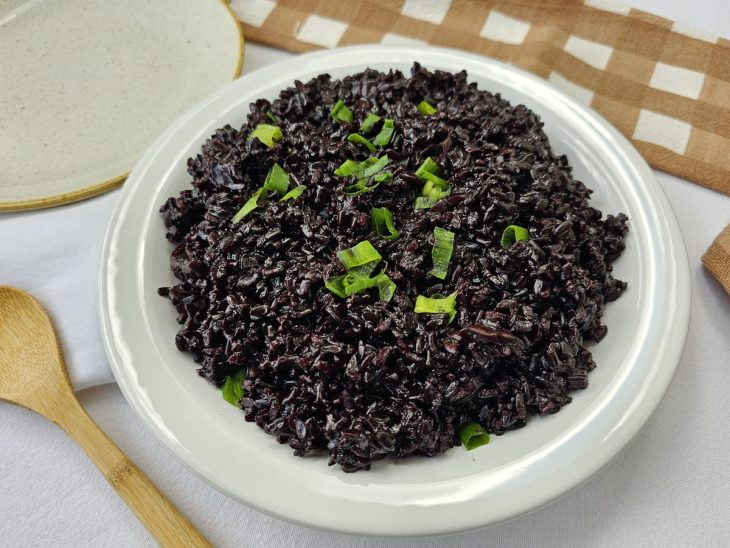 Arroz negro salpicado com cheiro-verde.