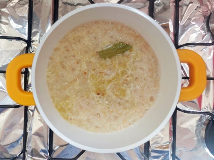 Arroz e temperos com água na panela.