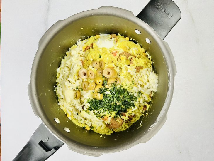 finalização do arroz temperado com cheiro verde, azeitona e queijo.
