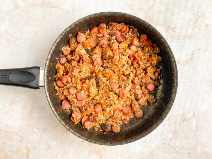 Tomate, arroz, sal, pimenta e páprica adicionados a frigideira.