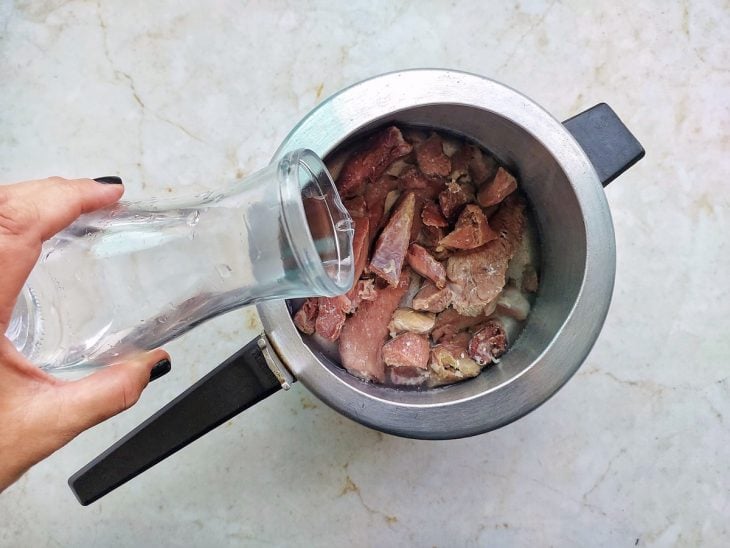 Carne seca e água adicionadas na panela de pressão.
