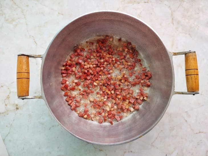 Cubinhos de bacon e calabresa fritando na panela.