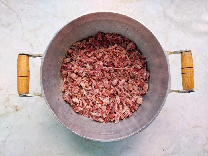 Carne seca e alho adicionados na panela.