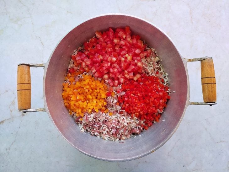 Pimentões e tomates adicionados na panela.