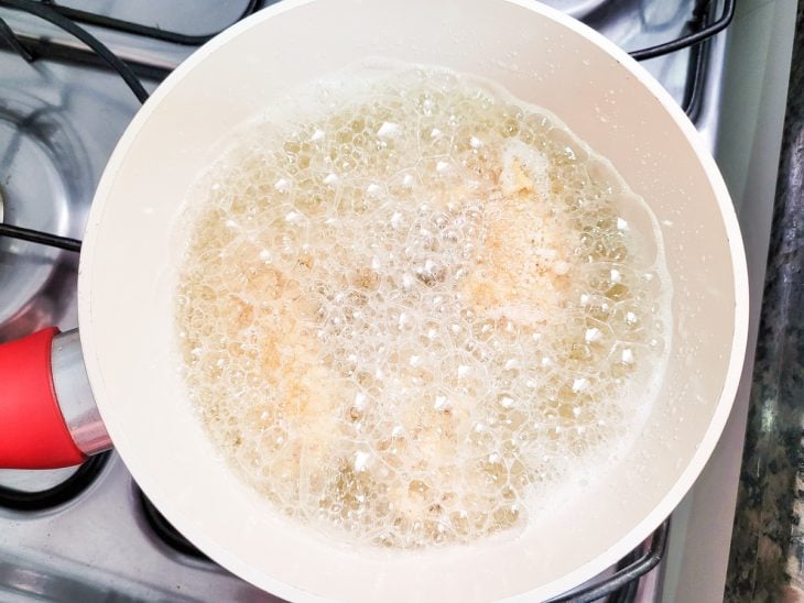 Uma panela contendo óleo quente fritando asinhas de frango.