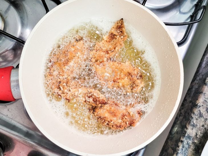 Uma panela contendo óleo quente fritando asinhas de frango.