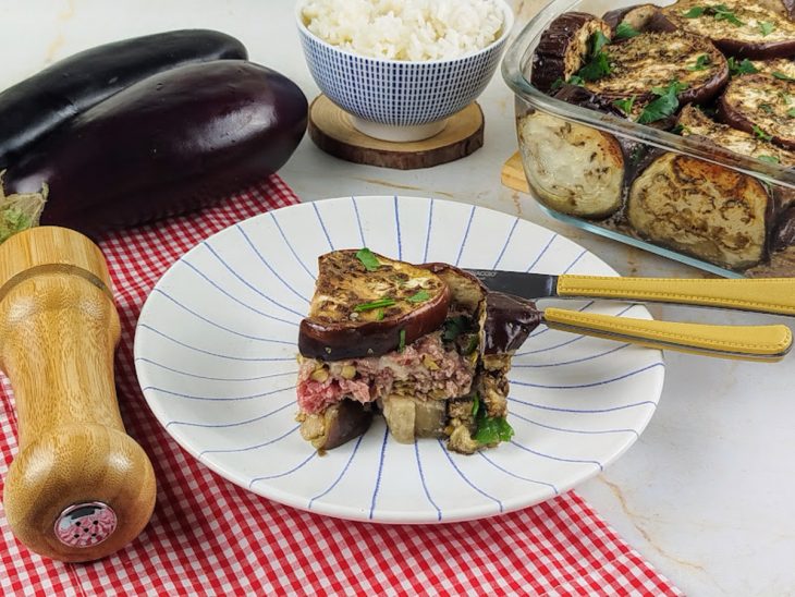 Fatia de assado de berinjela com carne moída em um prato, pronto para consumo.