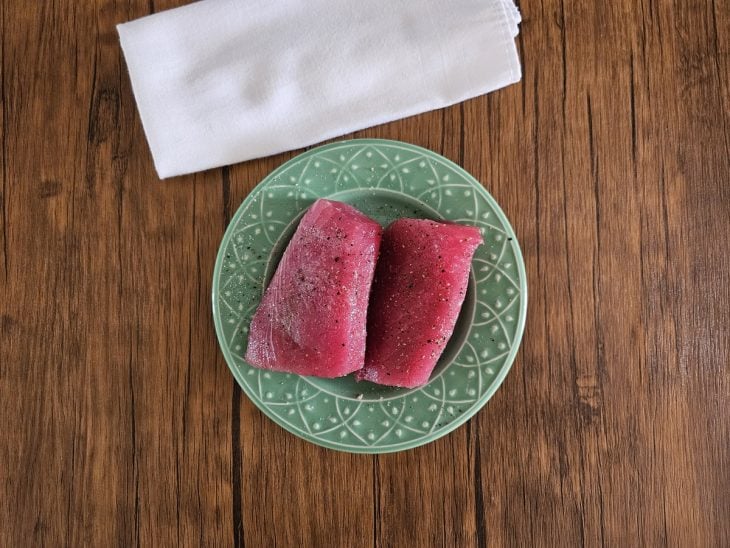 Um prato contendo duas postas de atum temperadas.