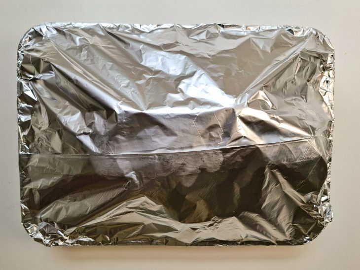 Assadeira com a ave, coberta com papel alumínio.