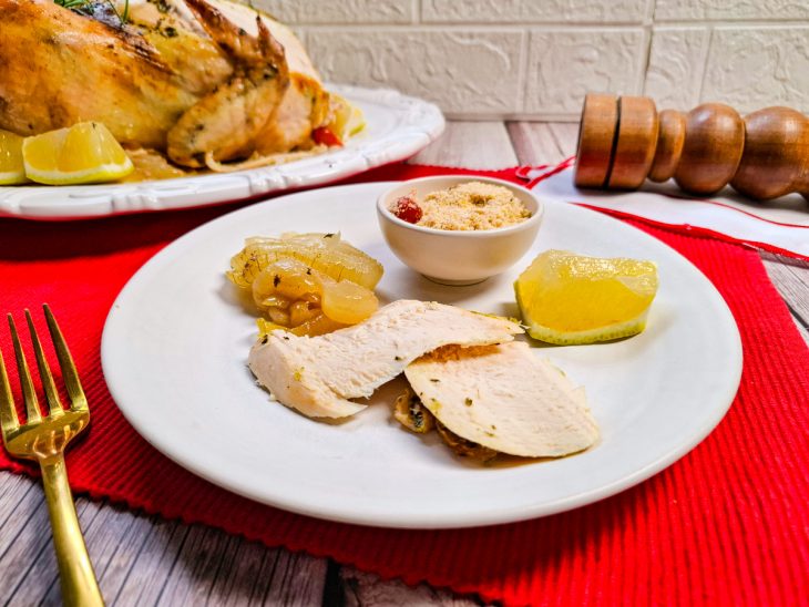 Ave pronta, pedaço do peito servido com o recheio de maça e cebola, acompanhada de farofa.