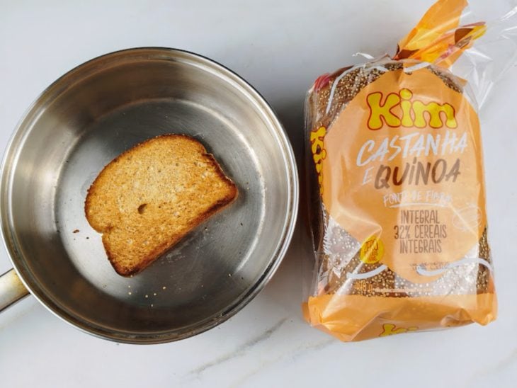 Fatia de pão dourada em uma frigideira com um fio de azeite.