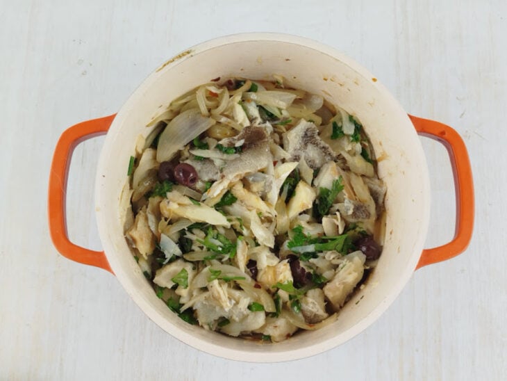 Bacalhau e azeitonas adicionados na panela com a cebola.