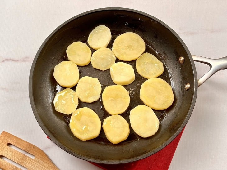 Uma frigideira com rodelas de batatas.