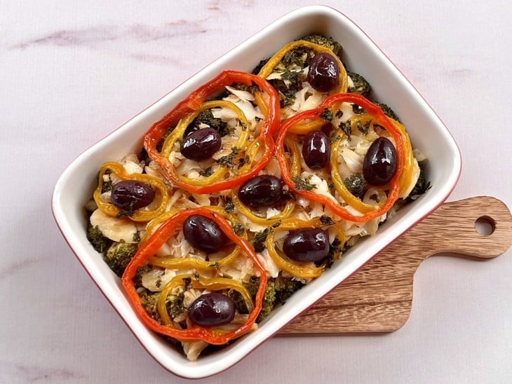 Um refratário contendo bacalhau com batata e brócolis.