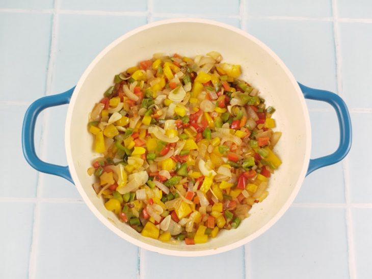 Pimentões e alho sendo refogados com azeite de dendê.