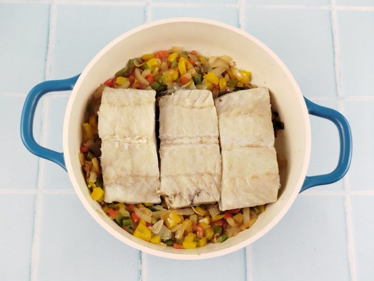 Camada de bacalhau adicionada sobre o refogado.