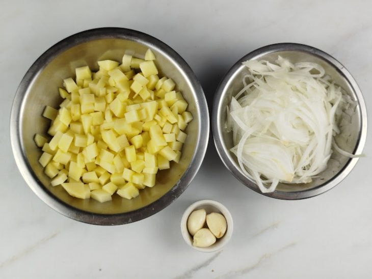Cebola, alho e batatas descascados e picados, em seus devidos recipientes.