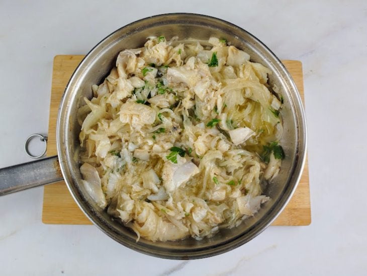 Frigideira com cebolas, lascas de bacalhau e temperos.