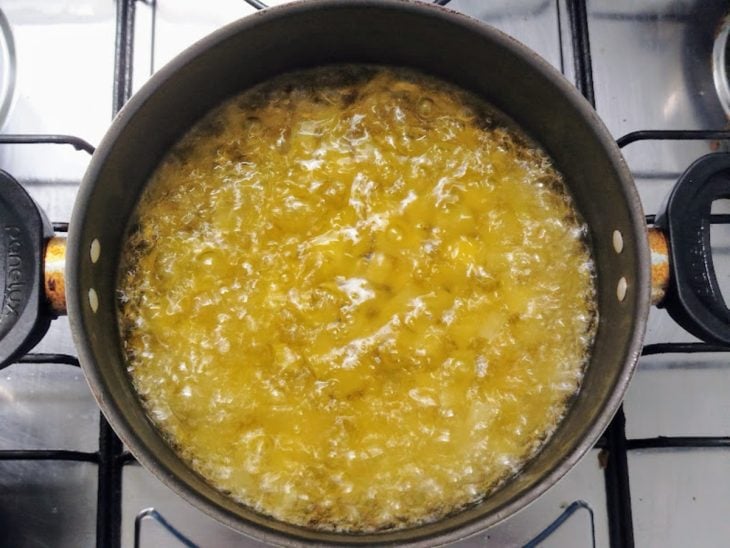 Panela com óleo e batatas a fritar.