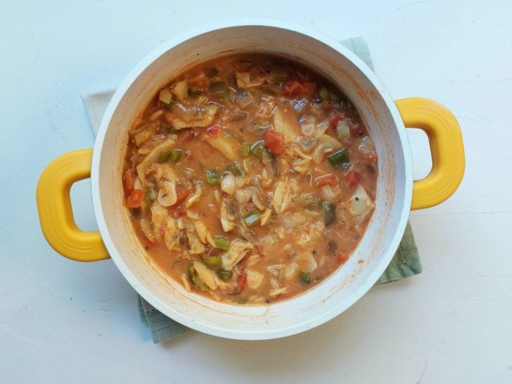 Uma panela contendo bacalhau dessalgado, alho, cebola, tomate, pimentão, molho de tomate, temperos e leite de coco.