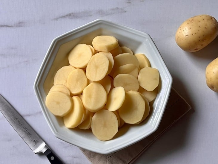 Um recipiente contendo batatas cortadas em rodelas.