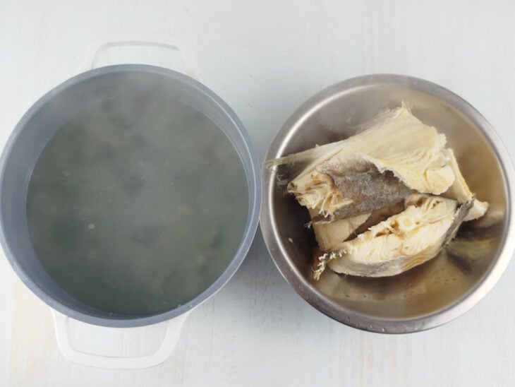 Bacalhau sendo cozido em água fervente dentro de uma panela.