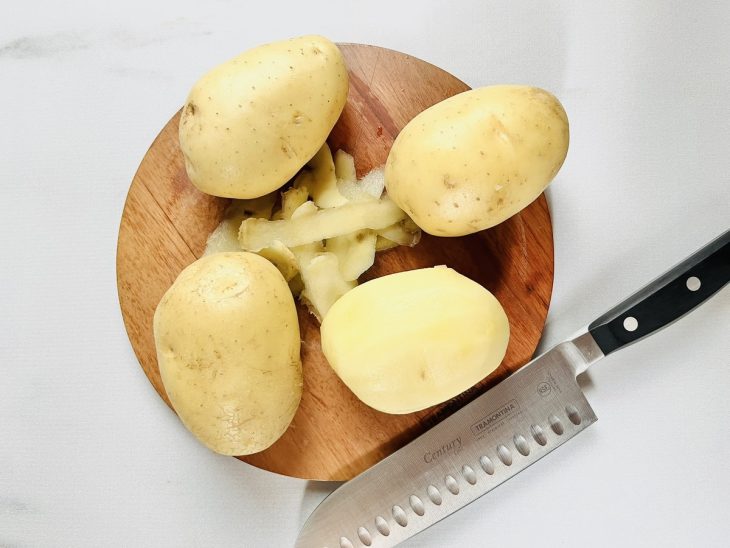 Batatas em uma tábua sendo descascadas.