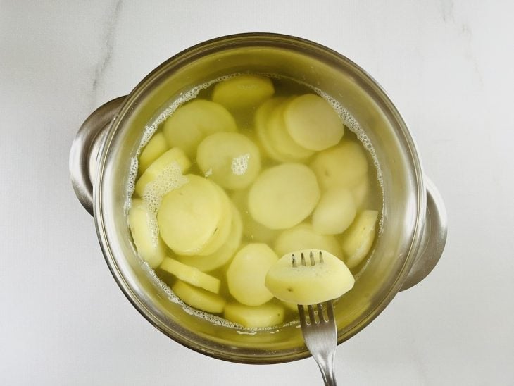 Uma panela com água e rodelas de batata.