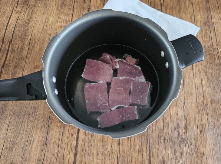 Uma panela de pressão contendo água e carne-seca.