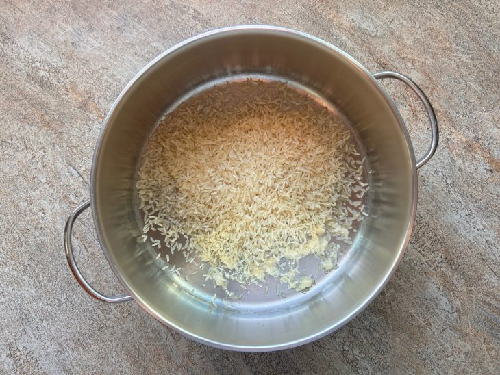 Na panela, alho, óleo e o arroz.