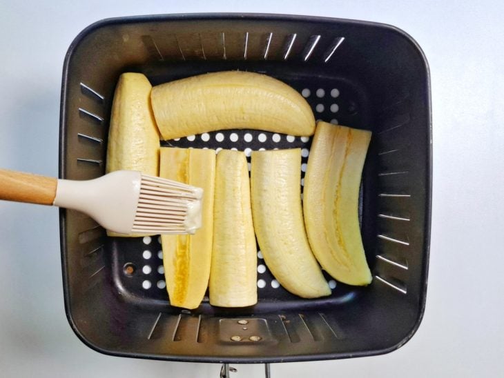 Bananas acomodadas no cesto da Air Fryer e manteiga pincelada no lado virado para cima.