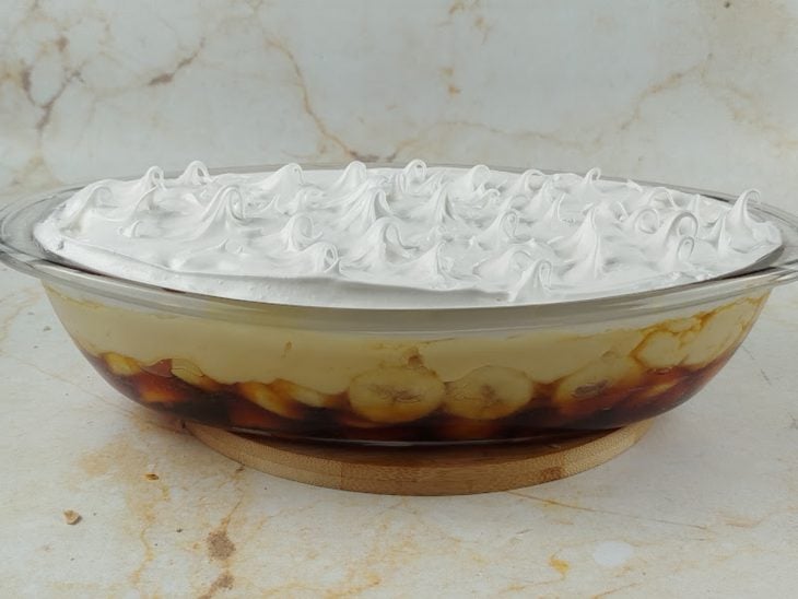Glacê despejado sobre a camada de creme branco no recipiente.