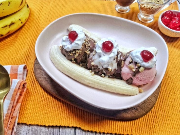 Banana split finalizada com chantilly e cereja pronta para consumo.