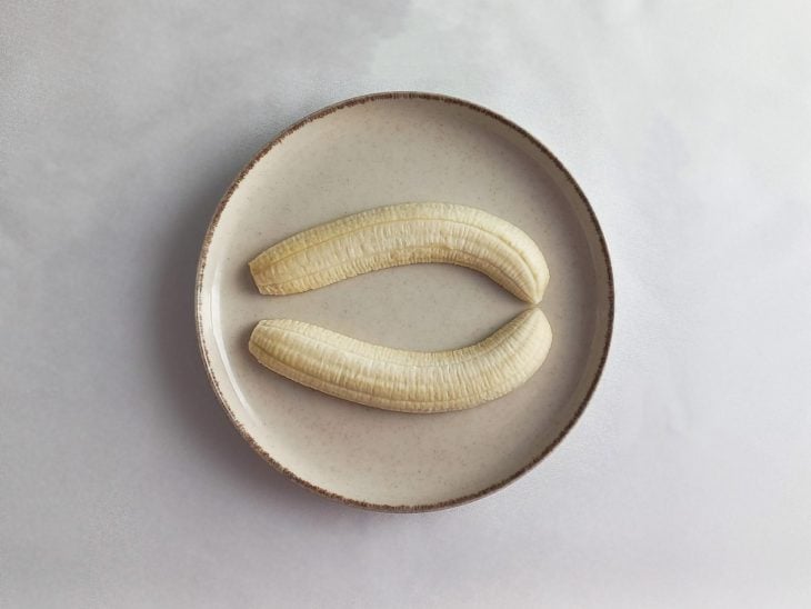 Um prato com a banana cortada ao meio.