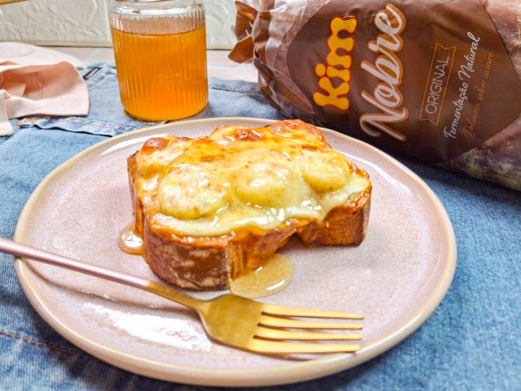 Toast finalizado, com o queijo derretido e mel escorrido por cima.