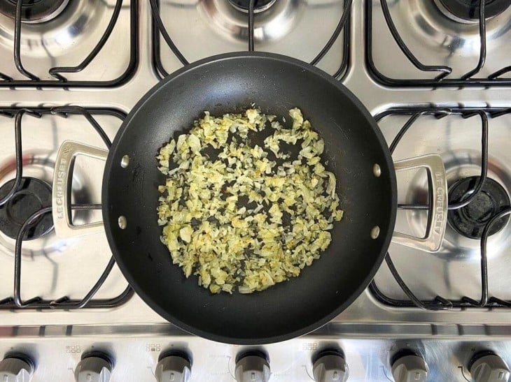 Uma frigideira com a cebola refogada.