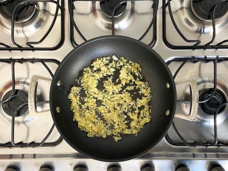 Uma frigideira com a cebola e alho refogados.