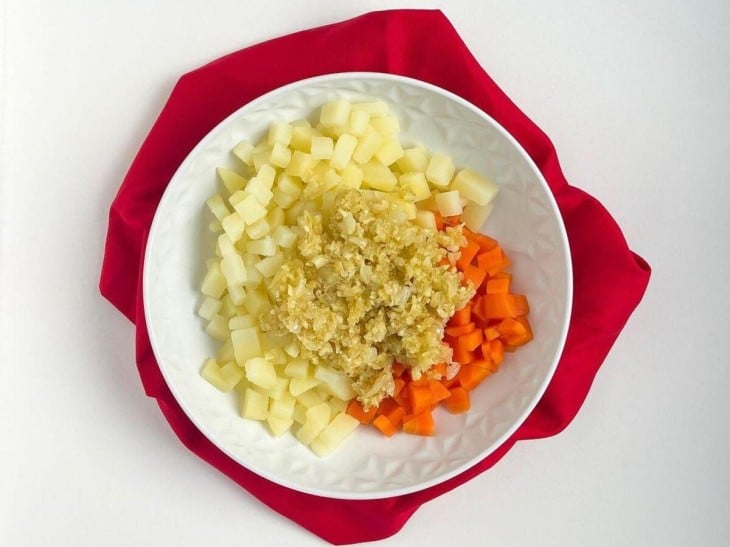 Um prato com as cenouras, batatas, cebola e alho.