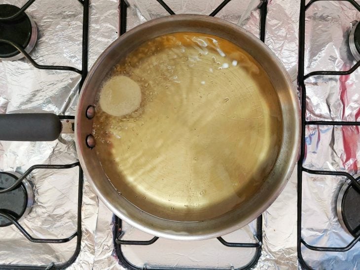 Uma panela contendo óleo quente com uma rodela de batata.