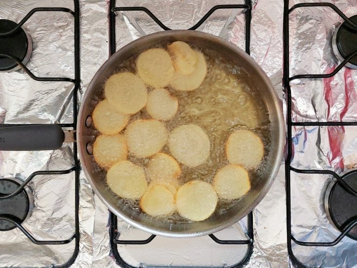 Uma panela fritando rodelas de batata no óleo.