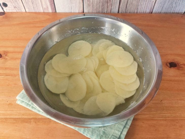 Um recipiente contendo água e batatas fatiadas.