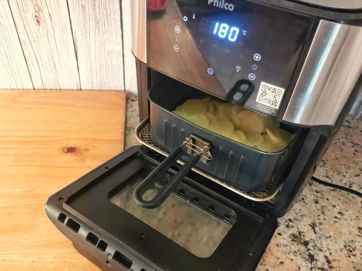 Uma airfryer contendo batatas fatiadas.